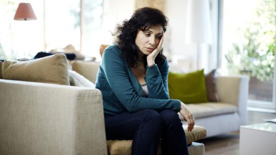 Femme inquiète assise sur son canapé